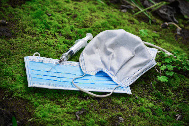 Two medical masks and a syringe on grass